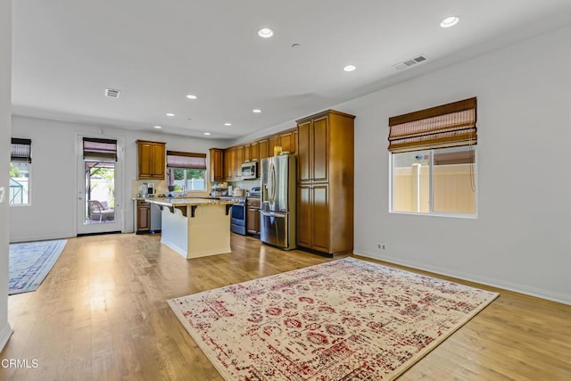 665 Tiber River Way, Oxnard, CA 93036 - kitchen with appliances with stainless steel finishes, a kitchen breakfast bar, a center island, light wood finished floors, and recessed lighting