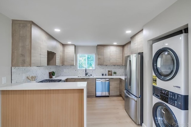 3629 Gilmore St, San Diego, CA 92113 - kitchen featuring appliances with stainless steel finishes, stacked washer / drying machine, a peninsula, light wood-type flooring, and light countertops