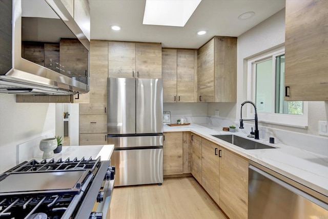 4107 Cole Way, San Diego, CA 92117 - kitchen featuring stainless steel appliances, light stone countertops, light brown cabinetry, light wood-type flooring, and a skylight