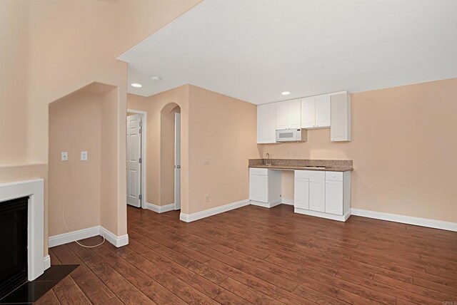 12672 Carmel Country Rd Unit 51, San Diego, CA 92130 - unfurnished living room featuring dark wood finished floors, a fireplace with flush hearth, recessed lighting, and arched walkways