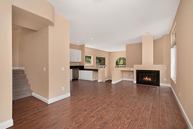12672 Carmel Country Rd Unit 51, San Diego, CA 92130 - unfurnished living room with dark wood-style flooring, a lit fireplace, and stairway