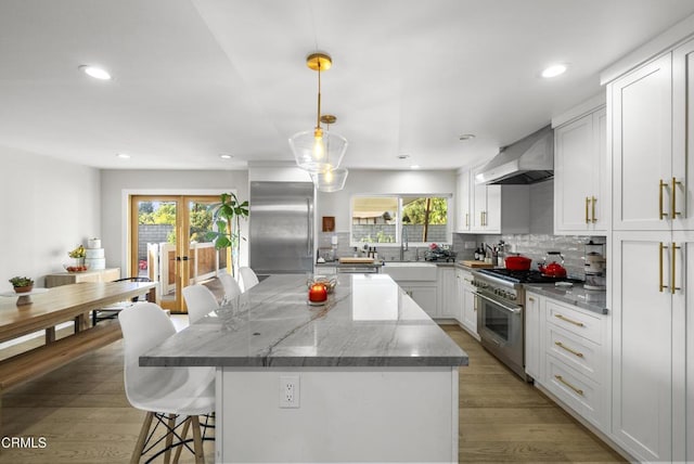 527 Keyser Rondo, Camarillo, CA 93010 - kitchen featuring high quality appliances, wall chimney range hood, a breakfast bar, decorative backsplash, and plenty of natural light