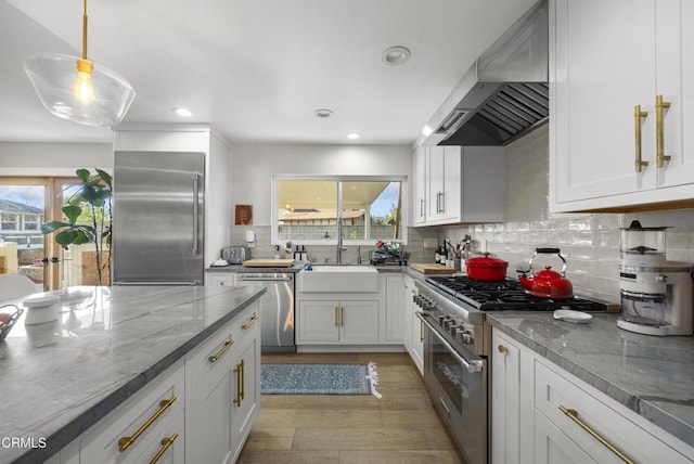 527 Keyser Rondo, Camarillo, CA 93010 - kitchen with wall chimney range hood, high end appliances, light wood finished floors, light stone countertops, and decorative backsplash