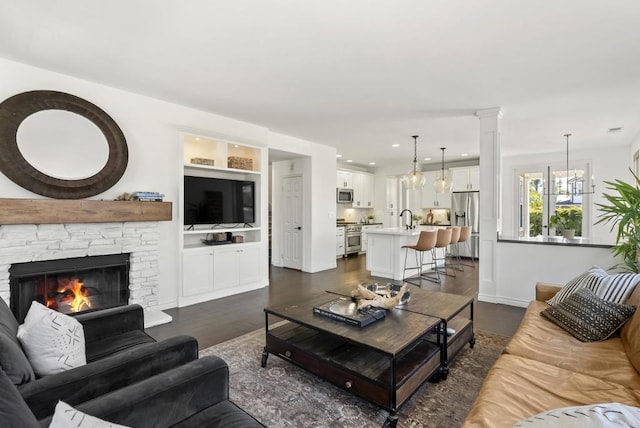 1480 Regatta Rd, Carlsbad, CA 92011 - living room with dark wood-style floors, a chandelier, a stone fireplace, and ornate columns
