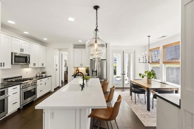 1480 Regatta Rd, Carlsbad, CA 92011 - kitchen featuring appliances with stainless steel finishes, dark wood finished floors, backsplash, a breakfast bar area, and white cabinetry