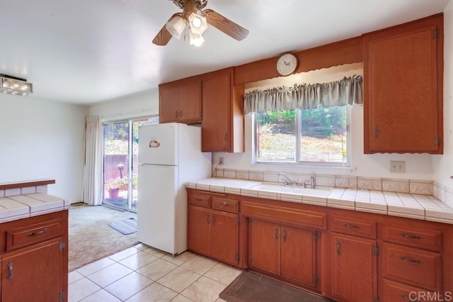 1970 El Prado Ave, Lemon Grove, CA 91945 - kitchen with freestanding refrigerator, brown cabinetry, a ceiling fan, tile countertops, and light tile patterned flooring
