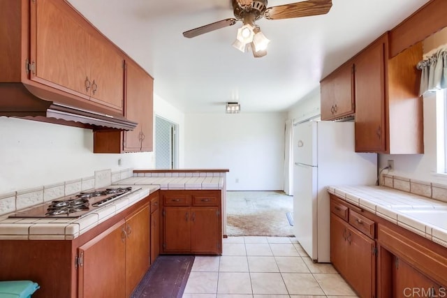 1970 El Prado Ave, Lemon Grove, CA 91945 - kitchen featuring stainless steel stovetop, tile counters, freestanding refrigerator, light colored carpet, and a peninsula