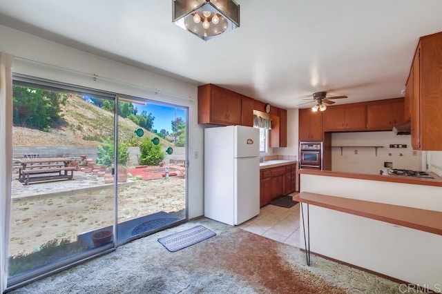 1970 El Prado Ave, Lemon Grove, CA 91945 - kitchen featuring freestanding refrigerator, under cabinet range hood, light carpet, ceiling fan, and brown cabinets