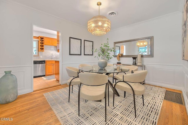 3671 Grayburn Rd, Pasadena, CA 91107 - dining area featuring light wood finished floors, crown molding, a chandelier, and a wainscoted wall