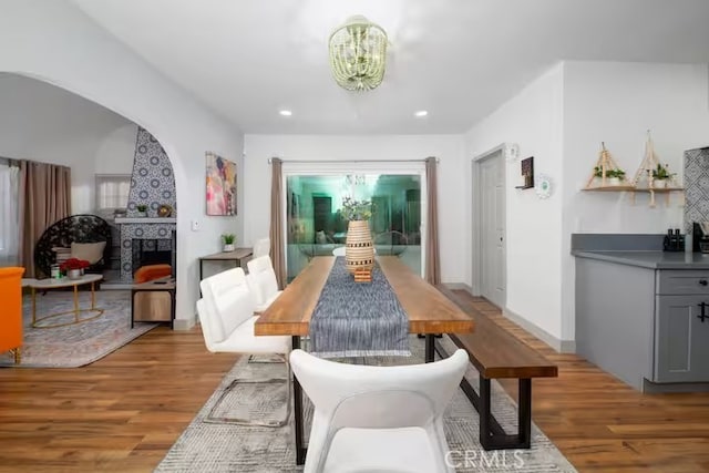 5743 Magnolia Ave, Riverside, CA 92506 - dining room featuring a chandelier, light wood-type flooring, a fireplace with raised hearth, recessed lighting, and arched walkways