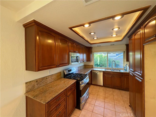25488 Orange Crest Way, Loma Linda, CA 92354 - kitchen with stainless steel appliances, a tray ceiling, light stone counters, and light tile patterned floors
