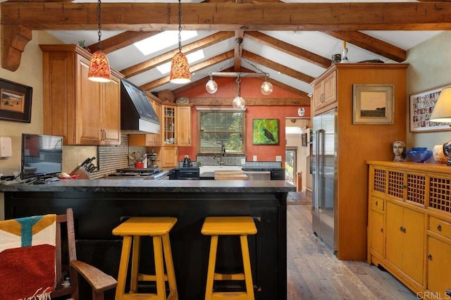 934 Arden Dr, Encinitas, CA 92024 - kitchen with premium range hood, high end fridge, dark countertops, light wood finished floors, and a peninsula