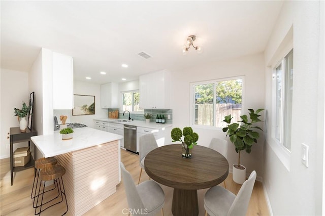 5955 Scheelite St, Jurupa Valley, CA 92509 - kitchen featuring appliances with stainless steel finishes, light wood finished floors, light countertops, white cabinets, and plenty of natural light