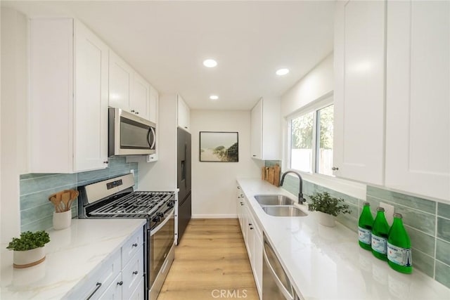 5955 Scheelite St, Jurupa Valley, CA 92509 - kitchen with stainless steel appliances, white cabinets, light stone counters, decorative backsplash, and light wood-type flooring