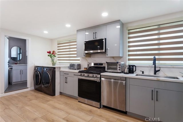 10535 Reseda Blvd, Porter Ranch, CA 91326 - kitchen featuring stainless steel appliances, washing machine and clothes dryer, gray cabinets, light wood-style flooring, and light countertops