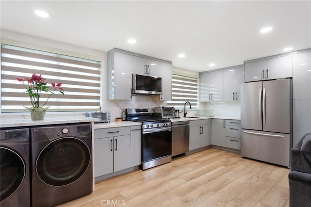 10535 Reseda Blvd, Porter Ranch, CA 91326 - kitchen featuring appliances with stainless steel finishes, gray cabinets, independent washer and dryer, light countertops, and light wood-style floors