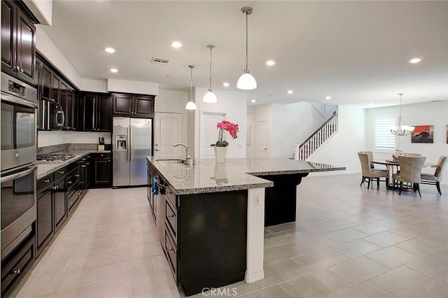 5621 Avocet Dr, Jurupa Valley, CA 91752 - kitchen featuring appliances with stainless steel finishes, a center island with sink, light stone counters, decorative light fixtures, and recessed lighting