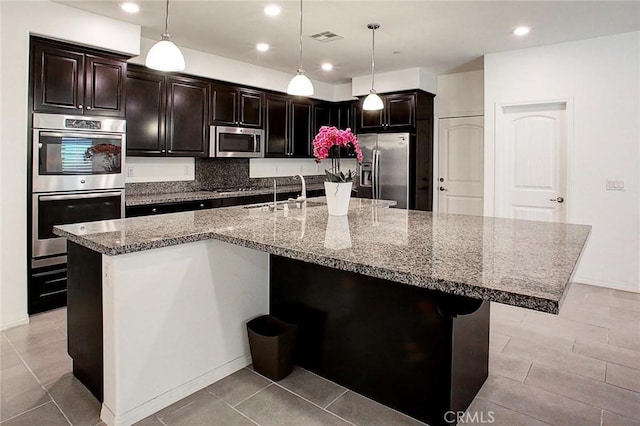 5621 Avocet Dr, Jurupa Valley, CA 91752 - kitchen with appliances with stainless steel finishes, a large island with sink, light stone countertops, recessed lighting, and decorative light fixtures