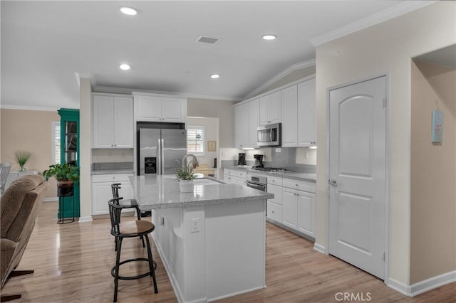 29183 Jacaranda, Lake Elsinore, CA 92530 - kitchen featuring stainless steel appliances, ornamental molding, white cabinets, vaulted ceiling, and a breakfast bar