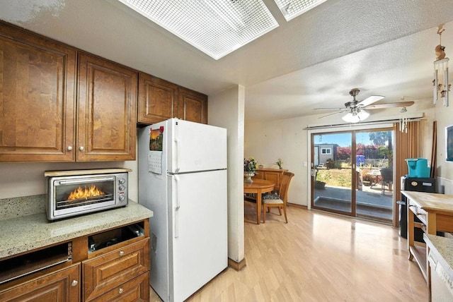 250 65th St, San Diego, CA 92114 - kitchen with freestanding refrigerator, light wood finished floors, a ceiling fan, brown cabinetry, and light stone counters