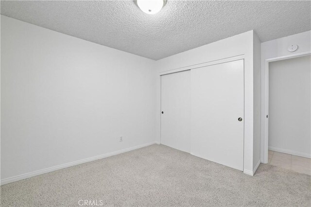 2065 N Shorewood Ave, Upland, CA 91784 - unfurnished bedroom featuring light carpet, a closet, and a textured ceiling