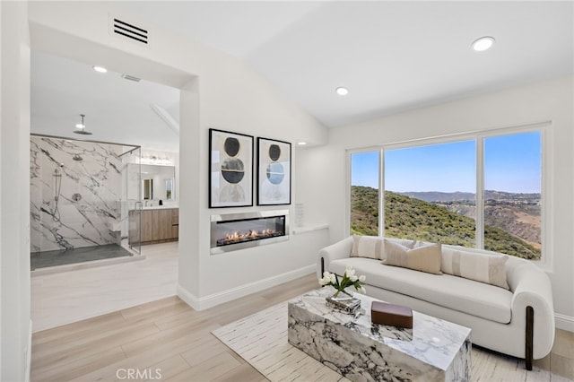 7 Sierra Vis, Laguna Niguel, CA 92677 - living room featuring a glass covered fireplace, light wood-style flooring, vaulted ceiling, and recessed lighting