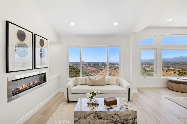 7 Sierra Vis, Laguna Niguel, CA 92677 - living room with healthy amount of natural light, a glass covered fireplace, light wood-style floors, a mountain view, and vaulted ceiling
