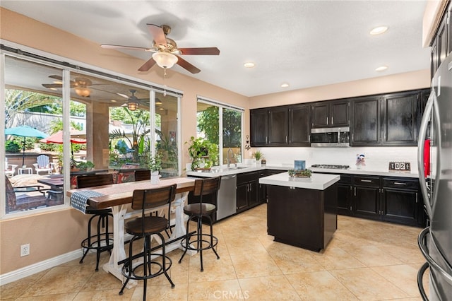 5601 Crestline Pl, Rancho Cucamonga, CA 91739 - kitchen featuring appliances with stainless steel finishes, dark cabinets, light countertops, ceiling fan, and a center island