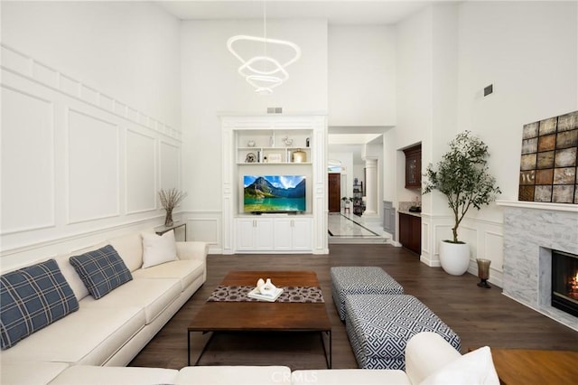 5914 Johnston Pl, Rancho Cucamonga, CA 91739 - living room featuring a decorative wall, a high ceiling, a lit fireplace, dark wood-style floors, and a wainscoted wall