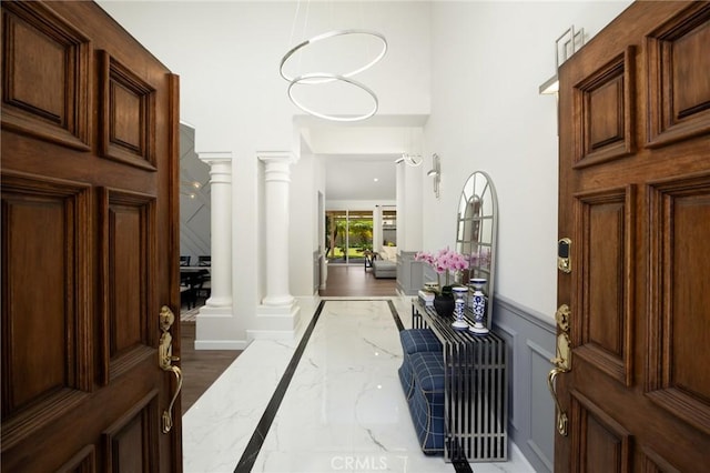 5914 Johnston Pl, Rancho Cucamonga, CA 91739 - entrance foyer with inlaid floor details, marble tiled flooring, decorative columns, a wainscoted wall, and a decorative wall