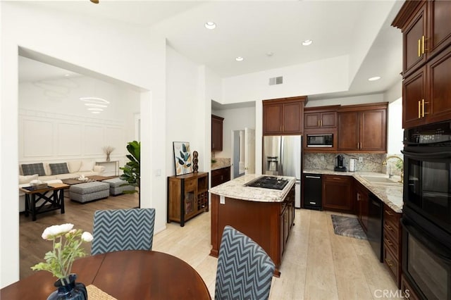 5914 Johnston Pl, Rancho Cucamonga, CA 91739 - kitchen with black appliances, light wood finished floors, decorative backsplash, a center island, and light stone counters