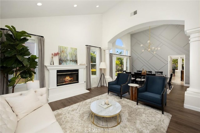 5914 Johnston Pl, Rancho Cucamonga, CA 91739 - living room with decorative columns, a towering ceiling, a glass covered fireplace, wood finished floors, and arched walkways