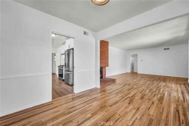 1014 W 185th St, Gardena, CA 90248 - unfurnished living room featuring light wood finished floors, a brick fireplace, and a textured ceiling