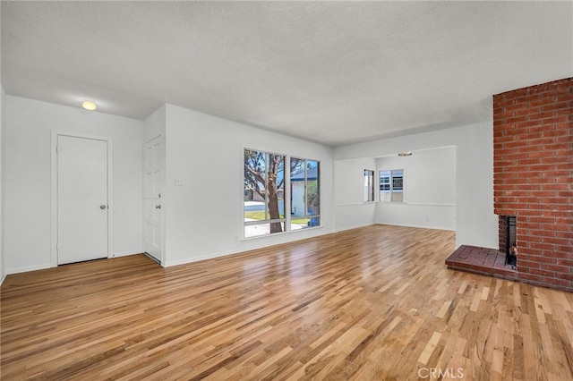 1014 W 185th St, Gardena, CA 90248 - unfurnished living room with a textured ceiling, light wood-type flooring, and a brick fireplace