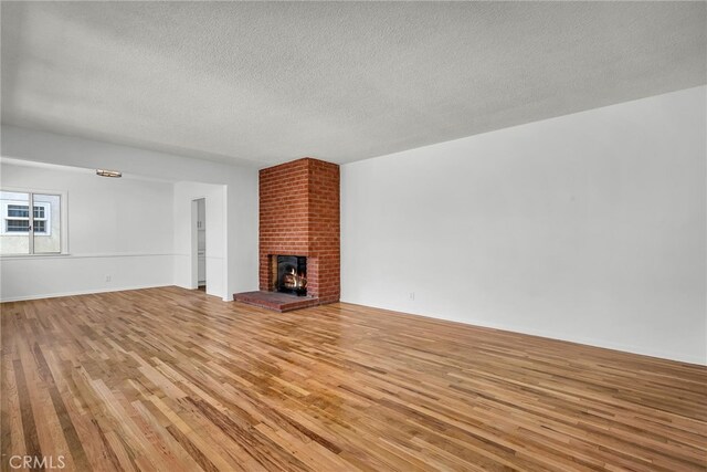 1014 W 185th St, Gardena, CA 90248 - unfurnished living room featuring light wood-style floors, a textured ceiling, and a fireplace