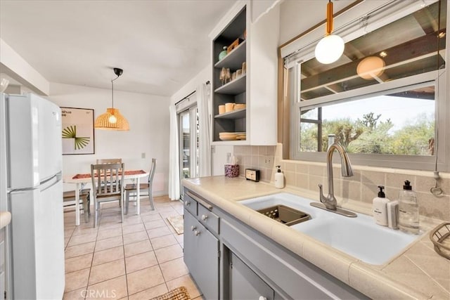 7638 Dumosa Ave, Yucca Valley, CA 92284 - kitchen with freestanding refrigerator, gray cabinets, light tile patterned flooring, open shelves, and decorative backsplash