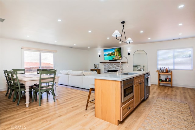 9140 Garden St, Rancho Cucamonga, CA 91701 - kitchen with appliances with stainless steel finishes, a fireplace, light wood-style flooring, open floor plan, and light countertops