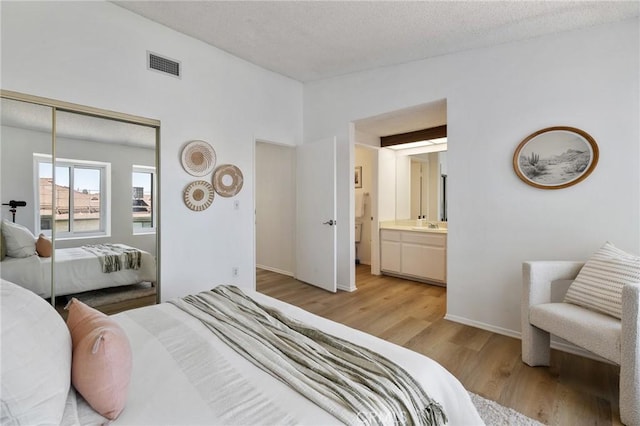 7038 De Celis Pl Unit 4, Van Nuys, CA 91406 - bedroom with light wood-style floors, a closet, a textured ceiling, connected bathroom, and vaulted ceiling