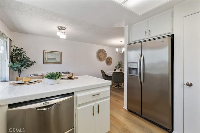 7038 De Celis Pl Unit 4, Van Nuys, CA 91406 - kitchen featuring stainless steel appliances, tile countertops, a textured ceiling, light wood-style floors, and a chandelier