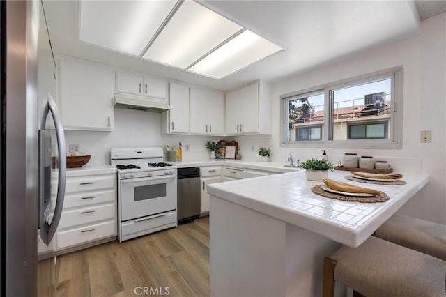 7038 De Celis Pl Unit 4, Van Nuys, CA 91406 - kitchen featuring white range with gas stovetop, stainless steel refrigerator with ice dispenser, a peninsula, premium range hood, and white cabinetry