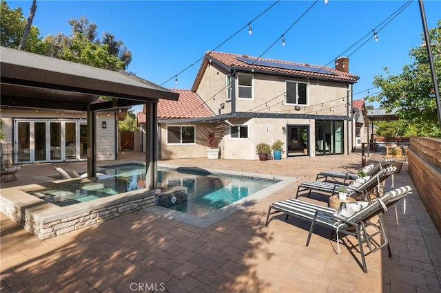 19022 Shamrock Ln, Yorba Linda, CA 92886 - back of house featuring a chimney, stucco siding, a tile roof, roof mounted solar panels, and a pool with connected hot tub