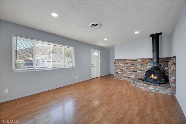 28296 Oregon Pl, Menifee, CA 92587 - unfurnished living room featuring a textured ceiling, wood finished floors, a wood stove, and recessed lighting