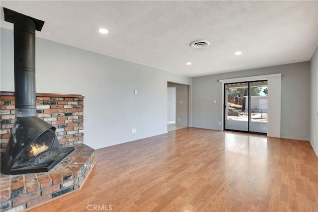 28296 Oregon Pl, Menifee, CA 92587 - unfurnished living room featuring wood finished floors, a wood stove, a textured ceiling, and recessed lighting