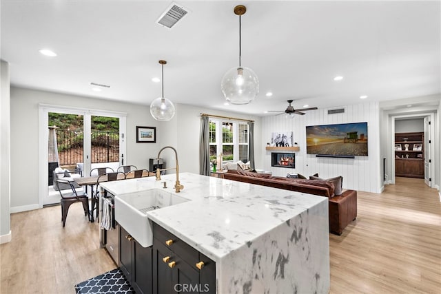 20 Becker, Ladera Ranch, CA 92694 - kitchen with light wood-style flooring, recessed lighting, light stone countertops, an island with sink, and decorative light fixtures