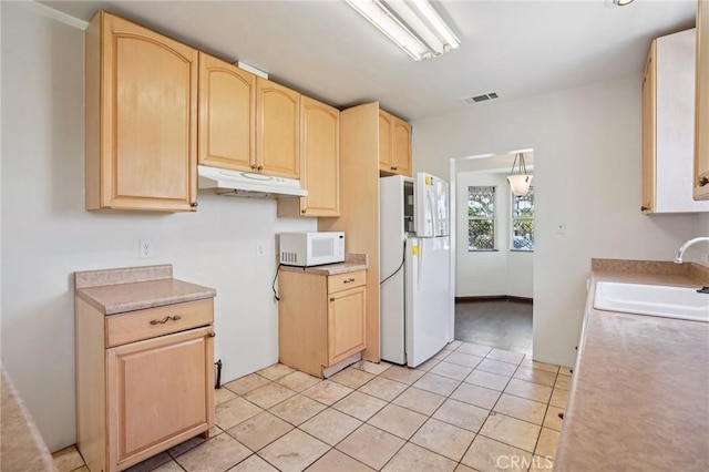 10018 San Vincente Ave, South Gate, CA 90280 - kitchen with white appliances, under cabinet range hood, light brown cabinetry, light countertops, and light tile patterned flooring