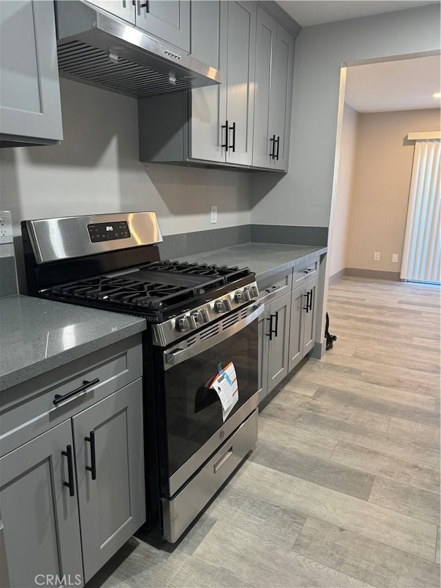 7445 Laurelgrove Ave Unit 2, North Hollywood, CA 91605 - kitchen with stainless steel range with gas stovetop, under cabinet range hood, gray cabinets, and light wood-style flooring