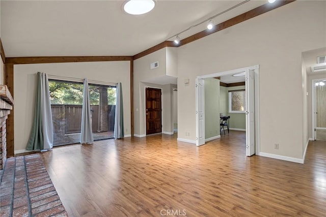 2665 Waverly Ct, Chico, CA 95973 - unfurnished living room featuring lofted ceiling, wood finished floors, rail lighting, and a brick fireplace