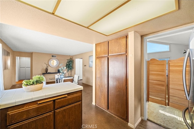 11551 Gladstone Cir, Fountain Valley, CA 92708 - kitchen with tile counters, stainless steel fridge, and dark flooring