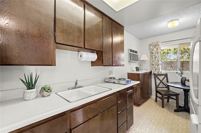 11551 Gladstone Cir, Fountain Valley, CA 92708 - kitchen with light countertops, freestanding refrigerator, a textured ceiling, a wall unit AC, and dark brown cabinetry
