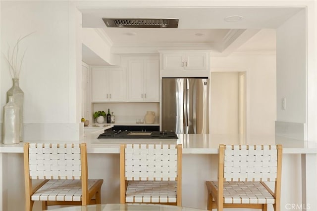 1585 Miramar Dr, Newport Beach, CA 92661 - kitchen with freestanding refrigerator, a peninsula, ornamental molding, white cabinets, and a breakfast bar